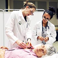 Professor pointing out the next area on of an older patient to a student during an examination