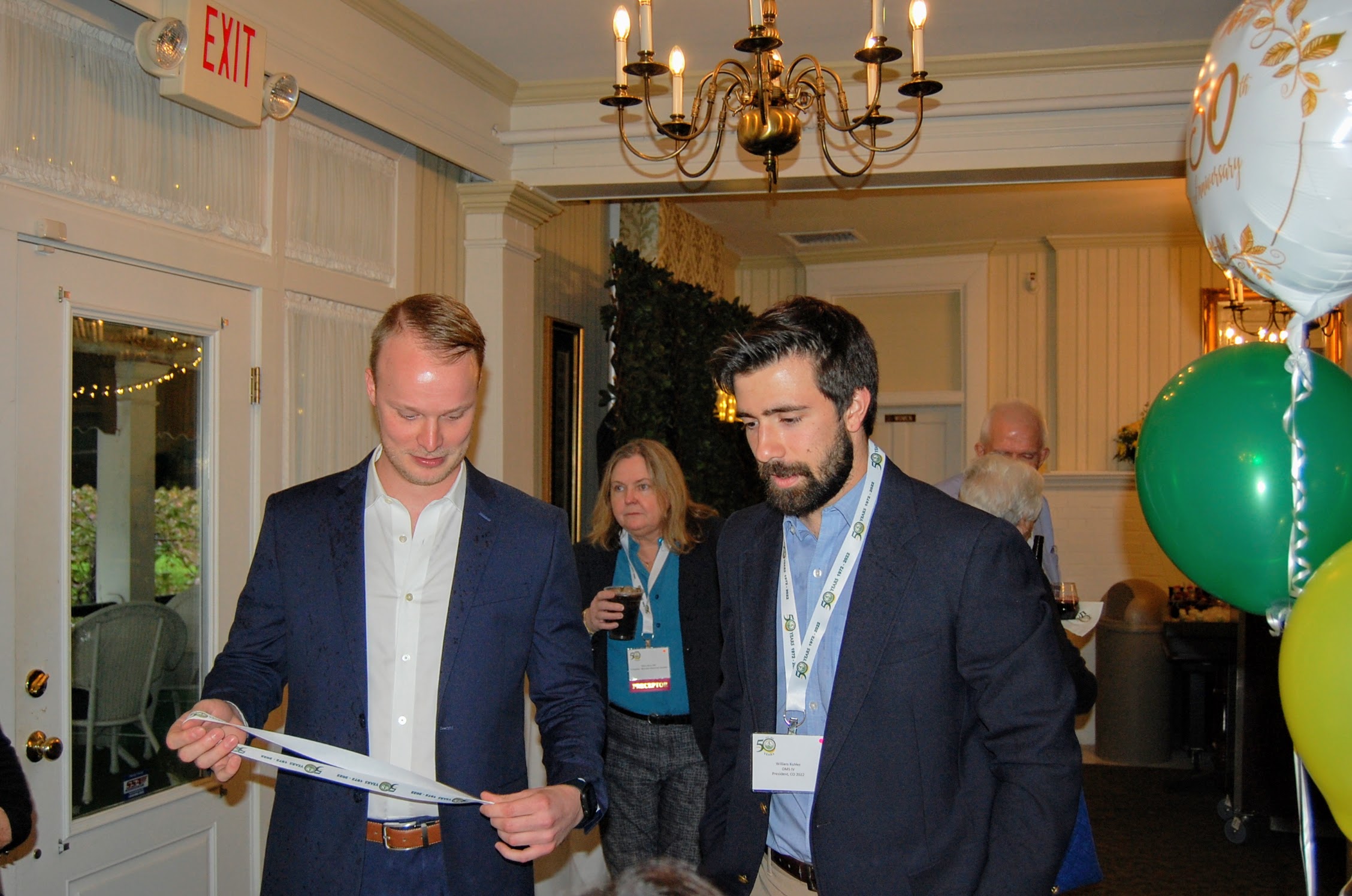 2 attendees checking in, one admires nametag lanyard