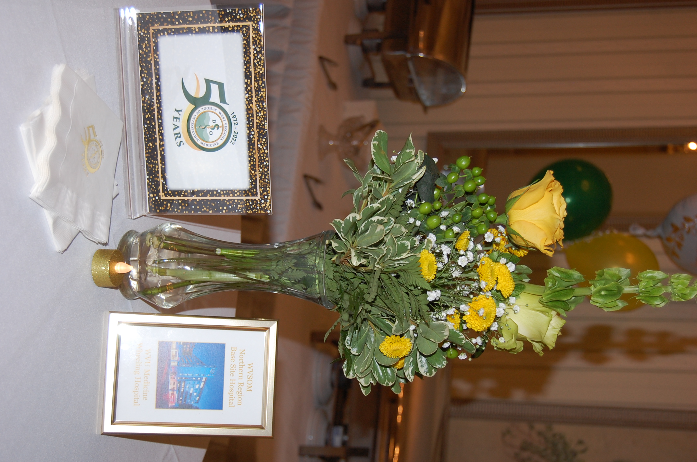 Table posed with flowers, 50 years of WVSOM decorations and Northern Region Base Site Hospital framed picture