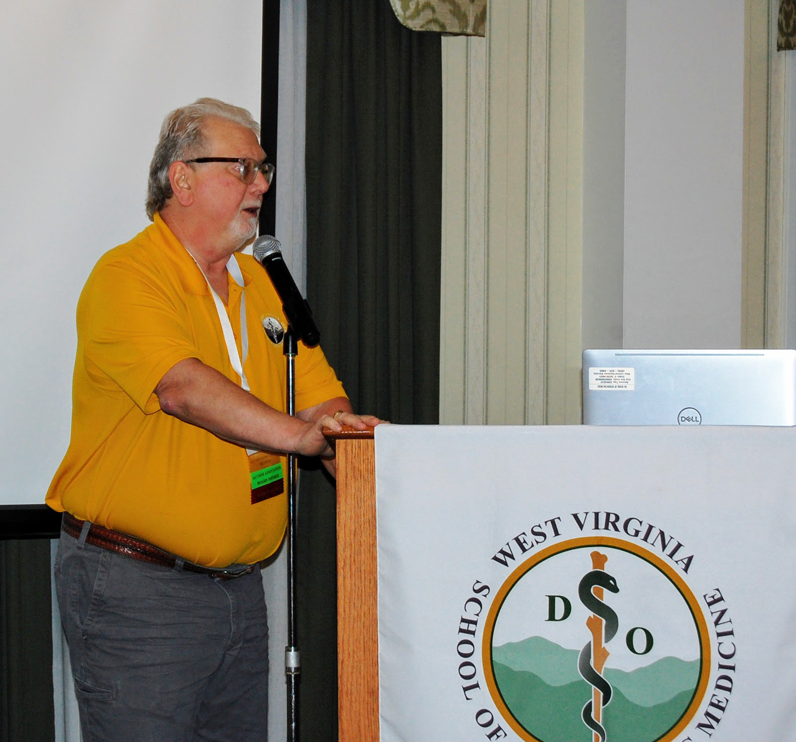 Man speaks into microphone at WVSOM logoed podium