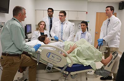 Professor and students around pregnant patient simulator