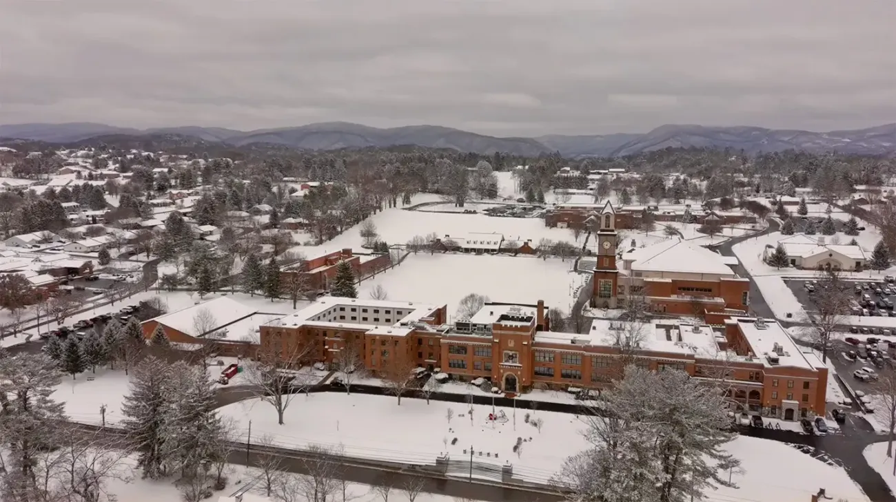 Aerial view of buildings and grounds covered in snow.