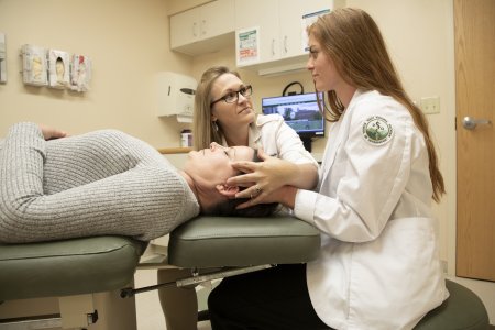 A physician and medical student perform osteopathic manipulative medicine on a patient.