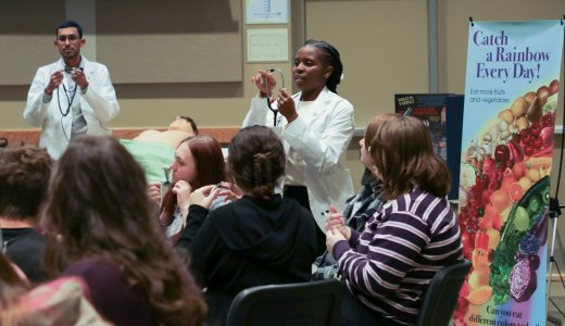 WVSOM students hold stethoscopes while teaching guests about heart and lung sounds