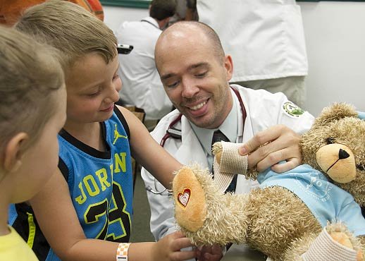 WVSOM Student using a teddy bear to show a child how to use a bandage wrap