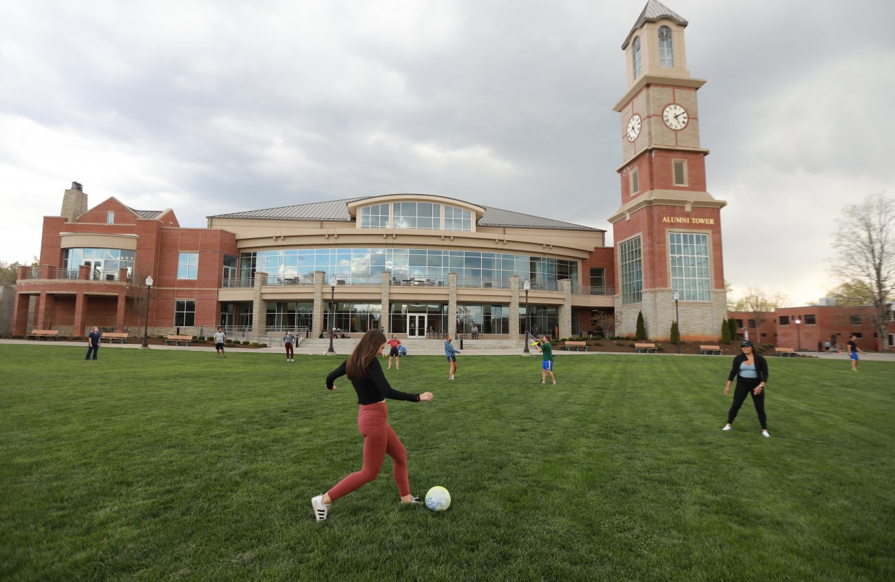 Students playing soccer in front of the student center on the parade field
