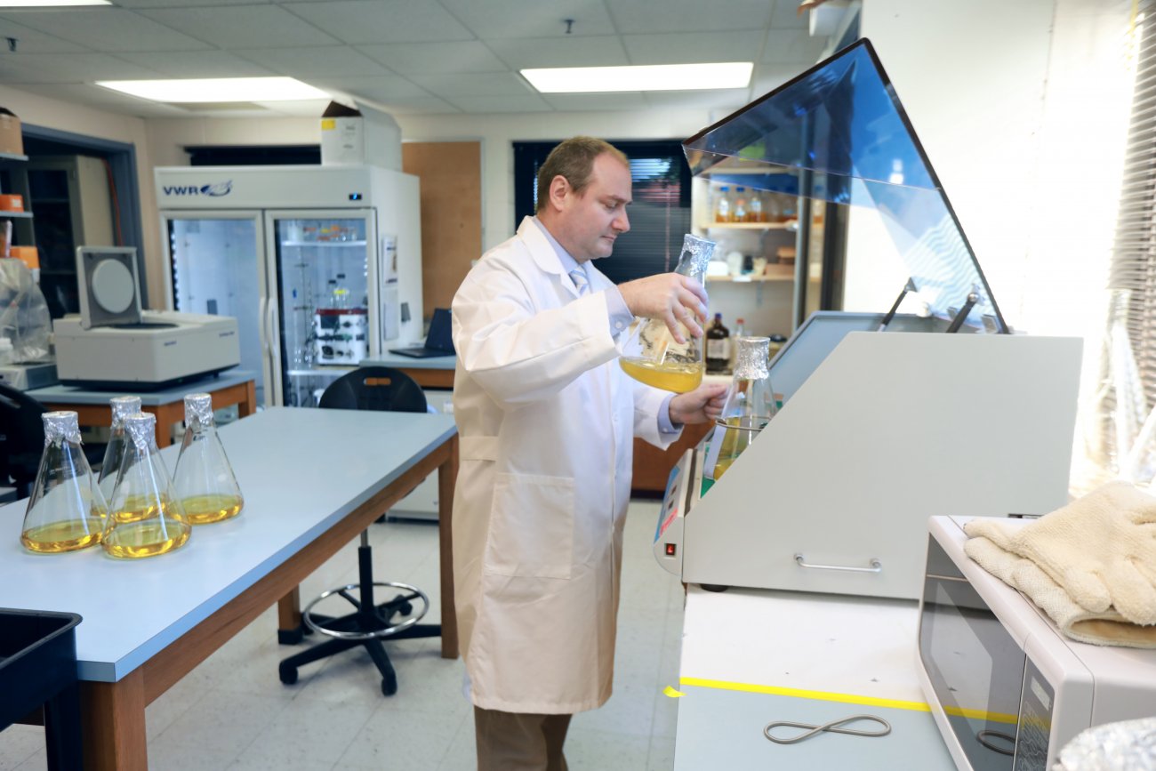 Dr. Marc Benson working in lab holding flask of liquid