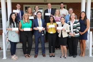 scholarship award winners displaying checks in front of WVSOM Foundation building