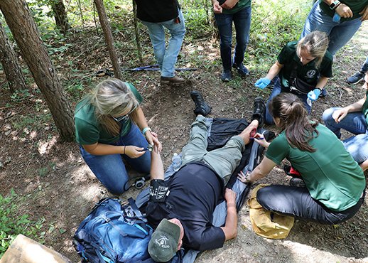 Students training for medical crisis in staged wooded area accident