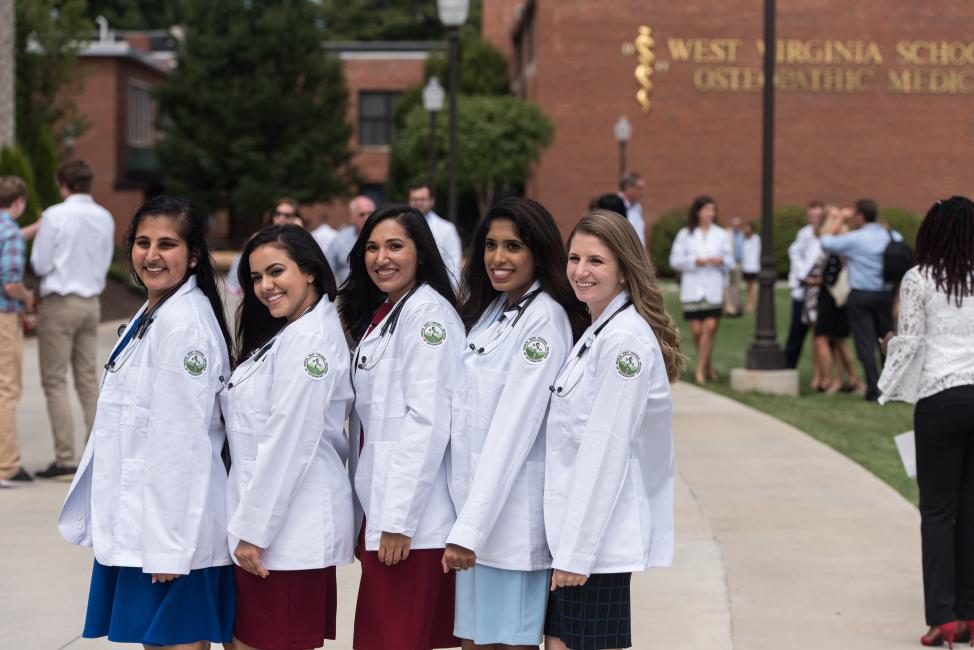 Students smiling and posing for a photo after receiving their white coats