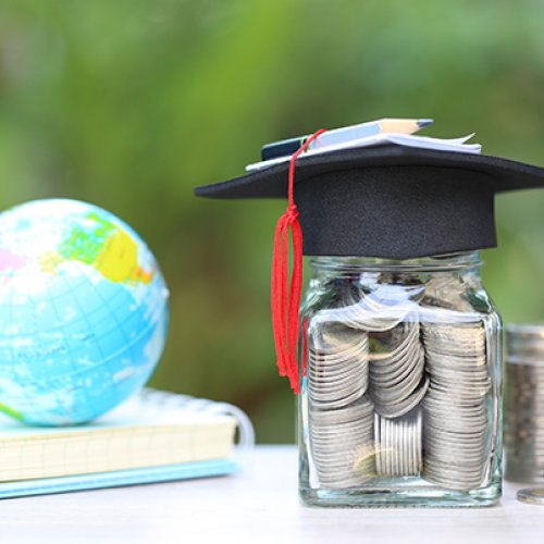 Graduation cap over jar of coins